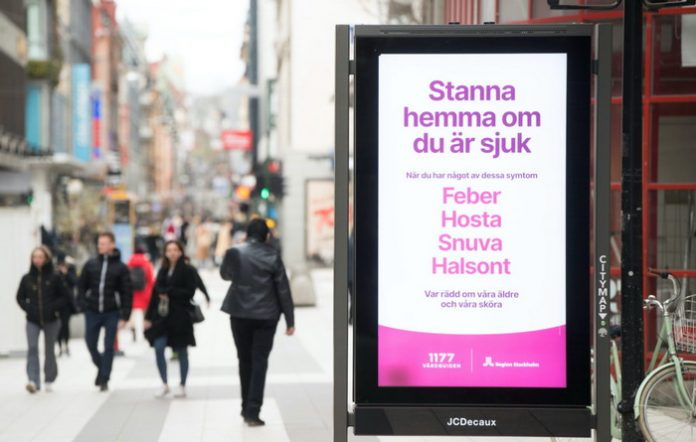 A billboard with information about coronavirus is seen, in a street with less pedestrian traffic than usual as a result of the coronavirus disease (COVID-19) outbreak in Stockholm