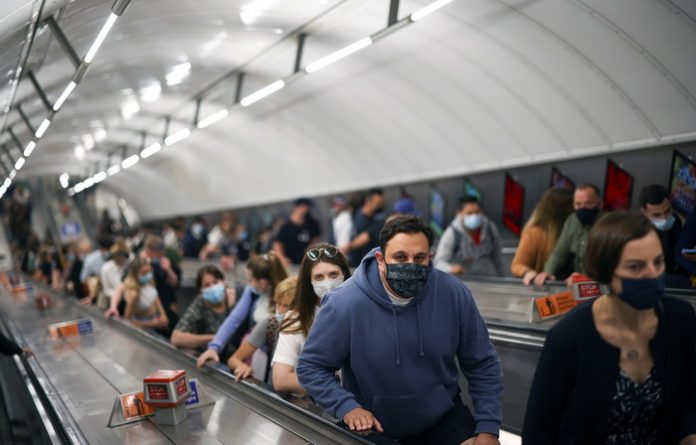 People ride an escalator in Leicester Square underground station, amid COVID-19 pandemic, in London
