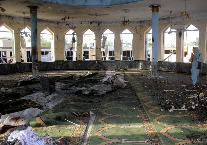 An Afghan man films inside a mosque after a blast, in Kunduz