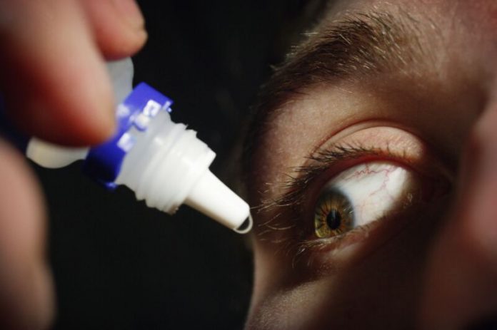 Young man applying eye drops
