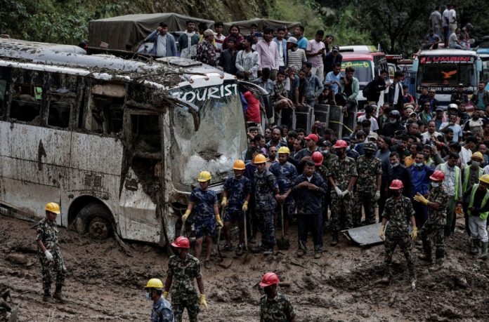 Rescue personnel work to retrieve the bodies of the victims from a landslide triggered by heavy rainfall in Dhading