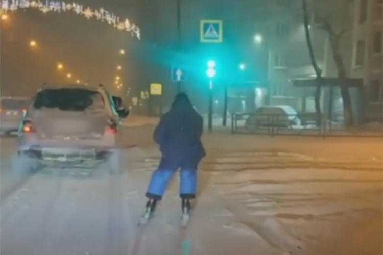Skijao ulicama grada vezan za automobil